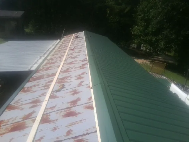 Old rusted panels beside newly installed green metal roofing — Wind Damage Roof Repair by Roofing Brothers in Babson Park