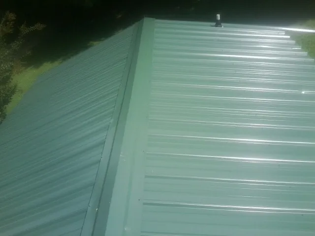 New green metal panels meeting at the ridge of a roof — Flat Roof Repair work by our crew in Babson Park