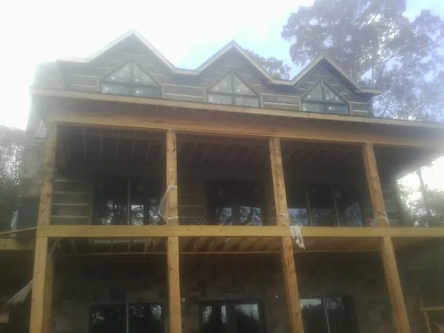 Dormers and porch framing on a large log home under construction — Roof Coating work by our crew in Babson Park