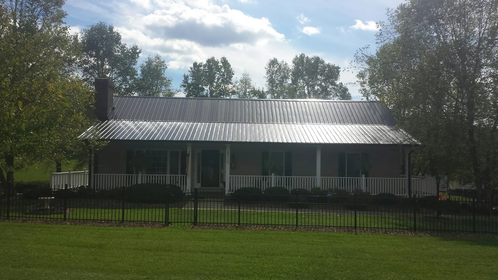Gray metal roof on a brick ranch with a full width front porch — Gutter Guard Installation work by our crew in Babson Park