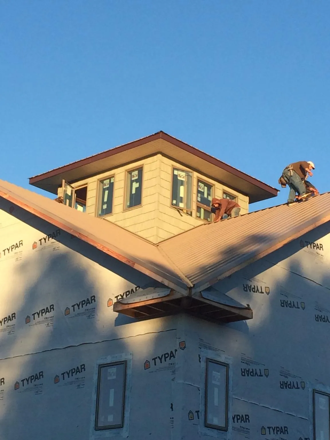Roofers working around a rooftop cupola on a new metal roof at sunset — Roof Waterproofing in Babson Park by Roofing Brothers